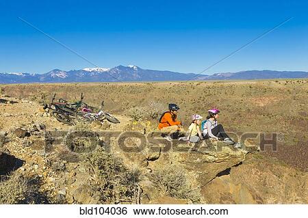 Stock Photograph - Family resting on cliff after mountain biking. Fotosearch