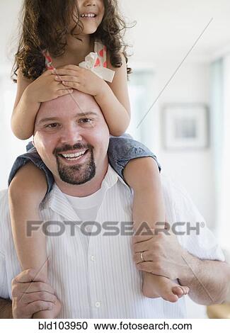 Stock Image - Father carrying daughter on shoulders. Fotosearch