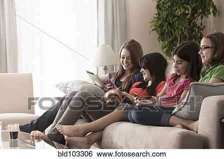 Stock Photograph - Friends hanging out on sofa together. Fotosearch