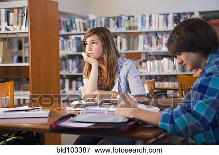Stock Photo - Frustrated student doing homework in library. Fotosearch