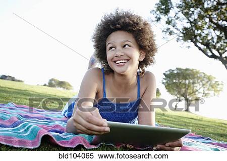 Stock Photography - Girl using digital tablet in park. Fotosearch
