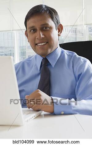 Stock Photo - Hispanic business using laptop. Fotosearch