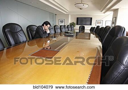 Stock Photo - Hispanic businessman sitting in empty conference room. Fotosearch