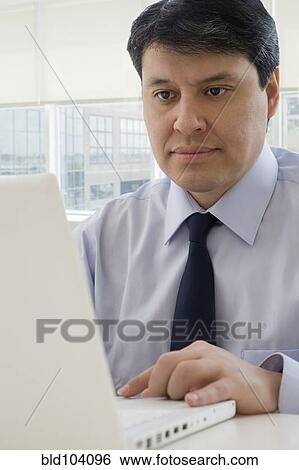 Stock Photograph - Hispanic businessman using laptop. Fotosearch