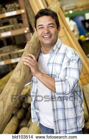 Picture - Hispanic carpenter carrying lumber. Fotosearch