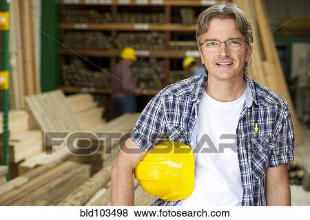 Stock Photo - Hispanic carpenter holding hard hat. Fotosearch