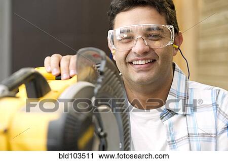 Hispanic carpenter standing with saw View Large Photo Image Stock Image - Hispanic carpenter standing with saw. Fotosearch