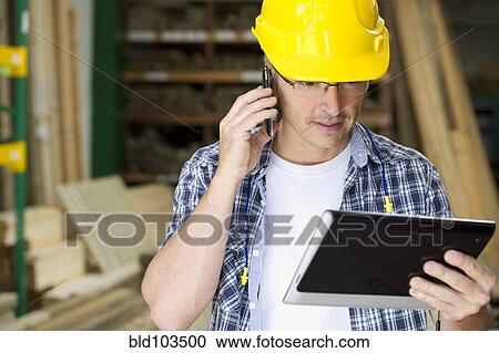 Hispanic carpenter using cell phone and digital tablet View Large Photo Image Stock Image - Hispanic carpenter using cell phone and digital tablet. Fotosearch