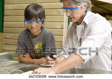 Stock Photo - Hispanic father and son in workshop. Fotosearch
