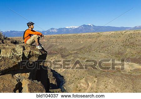 Hispanic man sitting on canyon cliff View Large Photo Image Stock Photo - Hispanic man sitting on canyon cliff. Fotosearch