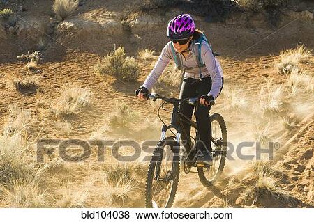 Stock Photo - Hispanic woman mountain biking. Fotosearch