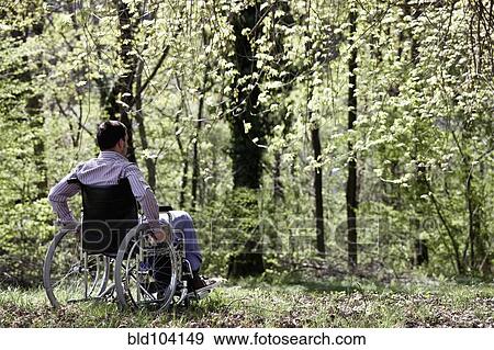 Stock Photo - Man sitting in wheelchair in woods. Fotosearch