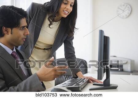 Stock Image - Mixed race business people looking at computer. Fotosearch