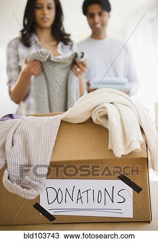 Stock Image - Mixed race couple donating clothing. Fotosearch