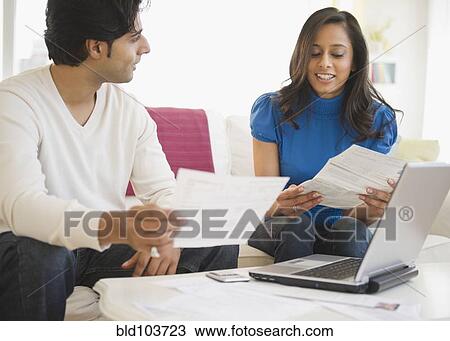 Stock Image - Mixed race couple paying bills online. Fotosearch