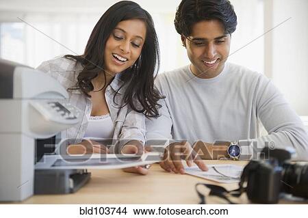 Picture - Mixed race couple printing documents. Fotosearch