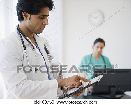 Stock Photo - Mixed race doctor using digital tablet. Fotosearch