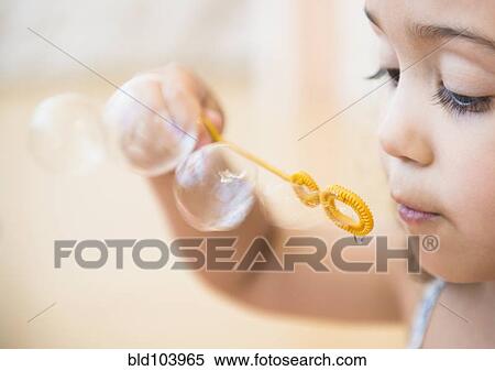 Stock Photography - Mixed race girl blowing bubbles. Fotosearch