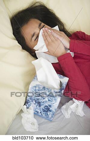 Stock Image - Mixed race girl blowing her nose. Fotosearch