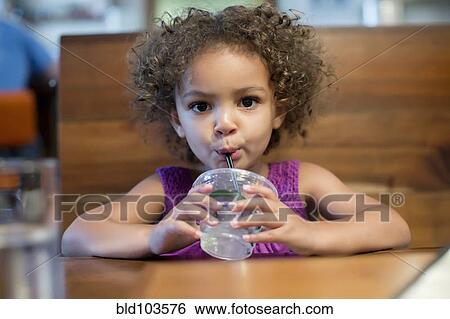 Stock Photograph - Mixed race girl drinking in restaurant. Fotosearch
