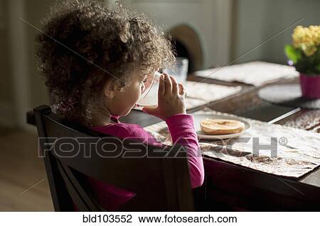 Stock Image - Mixed race girl eating breakfast. Fotosearch