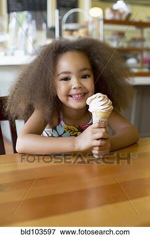 Stock Photo - Mixed race girl eating ice cream cone. Fotosearch