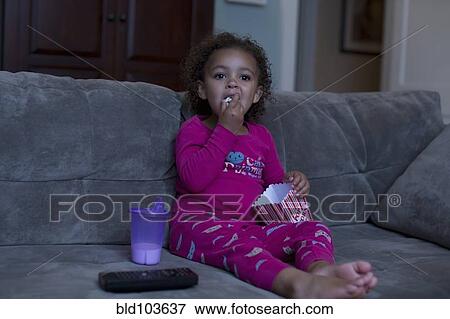 Mixed race girl eating popcorn and watching television View Large Photo Image Stock Photo - Mixed race girl eating popcorn and watching television. Fotosearch