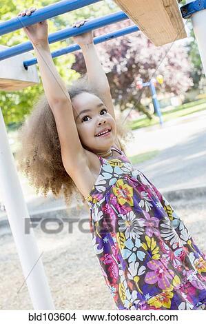 Picture - Mixed race girl hanging from bar. Fotosearch