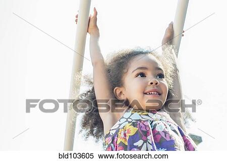 Stock Photography - Mixed race girl hanging from bar. Fotosearch