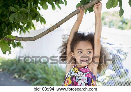 Mixed race girl hanging from branch View Large Photo Image Picture - Mixed race girl hanging from branch. Fotosearch