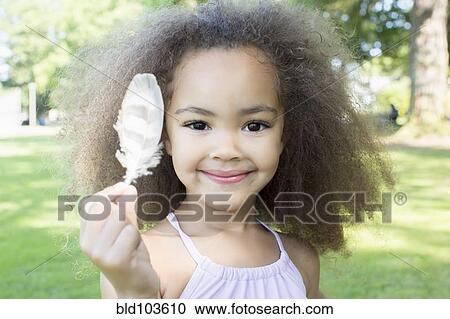 Stock Image - Mixed race girl holding a feather. Fotosearch