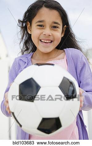Stock Image - Mixed race girl holding soccer ball. Fotosearch