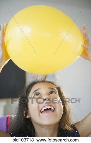 Mixed race girl holding yellow balloon View Large Photo Image Stock Photo - Mixed race girl holding yellow balloon. Fotosearch