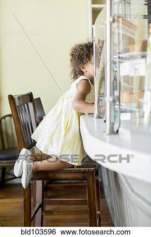 Mixed race girl kneeling at counter View Large Photo Image Stock Photograph - Mixed race girl kneeling at counter. Fotosearch