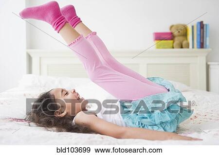 Stock Photo - Mixed race girl laying on bed. Fotosearch