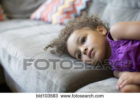 Stock Image - Mixed race girl laying on sofa. Fotosearch