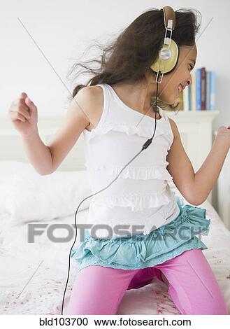 Stock Image - Mixed race girl listening to music on headphones. Fotosearch