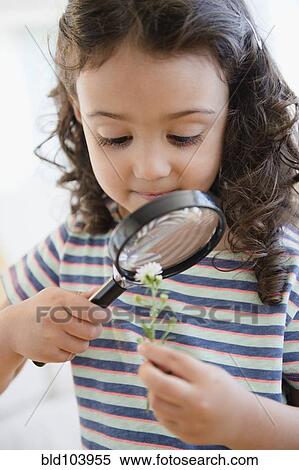 Stock Photography - Mixed race girl looking at flower with magnifying glass. Fotosearch