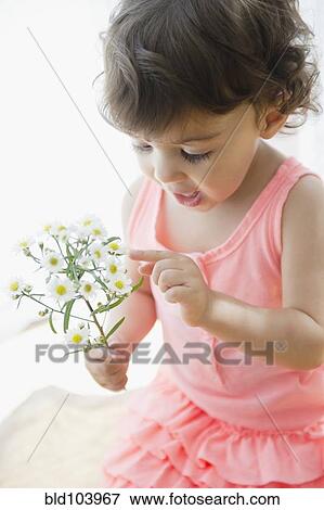 Stock Photo - Mixed race girl looking at flowers. Fotosearch