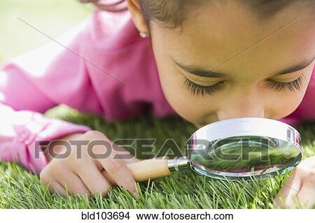 Mixed race girl looking at grass with magnifying glass View Large Photo Image Picture - Mixed race girl looking at grass with magnifying glass. Fotosearch