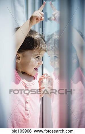 Stock Photograph - Mixed race girl looking out window. Fotosearch