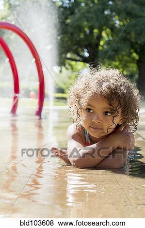 Stock Photo - Mixed race girl playing in fountain. Fotosearch