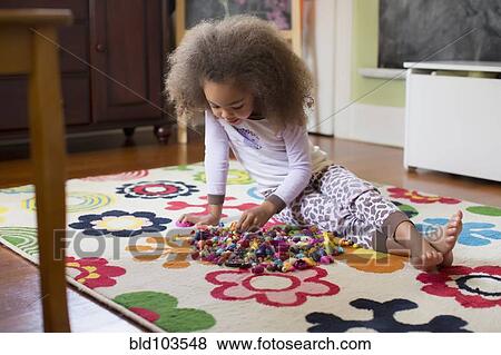 Mixed race girl playing with toys on floor View Large Photo Image Stock Photo - Mixed race girl playing with toys on floor. Fotosearch