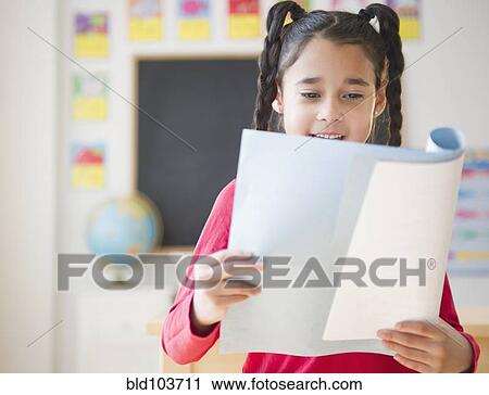 Stock Image - Mixed race girl reading report in school. Fotosearch