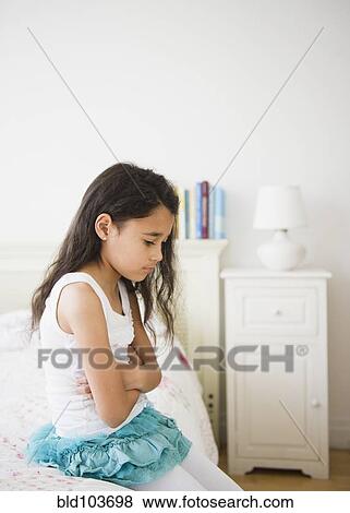 Mixed race girl sitting on bed View Large Photo Image Stock Photo - Mixed race girl sitting on bed. Fotosearch