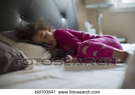 Stock Image - Mixed race girl sleeping in bed. Fotosearch