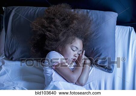 Stock Image - Mixed race girl sleeping in bed. Fotosearch
