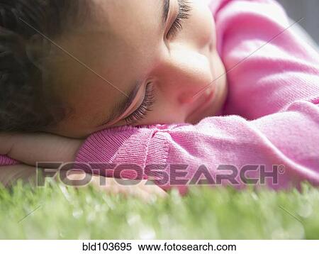 Stock Photography - Mixed race girl sleeping in grass. Fotosearch