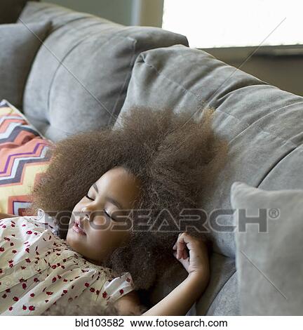Stock Image - Mixed race girl sleeping on sofa. Fotosearch