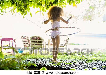 Stock Image - Mixed race girl twirling plastic hoop. Fotosearch